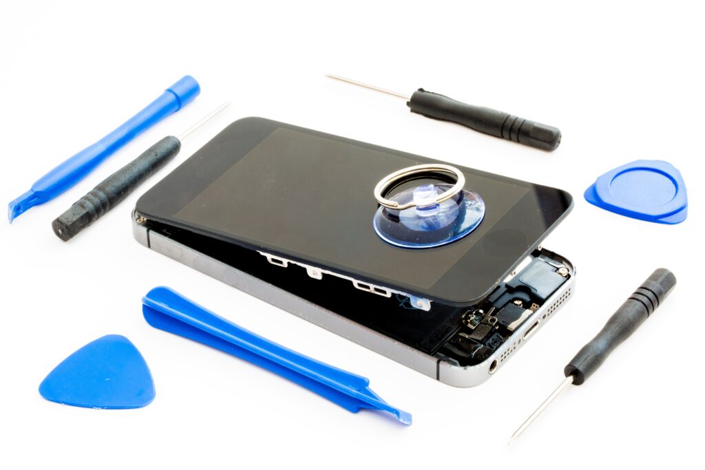 A damaged smartphone with the tools needed for replacement  or repair on an isolated white background